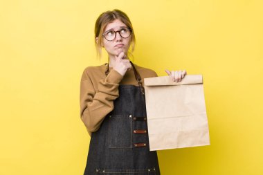 Kızıl saçlı güzel kadın düşünüyor, kuşkulu ve şaşkın hissediyor. teslimat paket servis kavramı