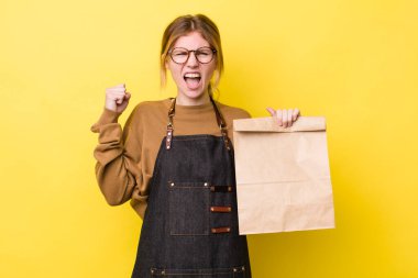 Kızıl saçlı güzel bir kadın sinirli bir ifadeyle agresif bir şekilde bağırıyor. teslimat paket servis kavramı