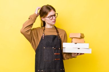 Kızıl saçlı güzel kadın şaşkın ve kafası karışık, kaşınan bir kafa hissediyor. Fast food yumuşak olsun.
