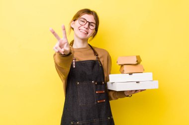 Kızıl saçlı güzel kadın gülümsüyor ve mutlu görünüyor, zafer ya da barış işareti yapıyor. Fast food yumuşak olsun.