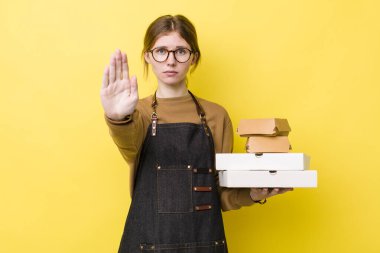 Kızıl saçlı güzel kadın ciddi görünüyor. Avuç içini gösteriyor. Durdurma hareketi yapıyor. Fast food yumuşak olsun.