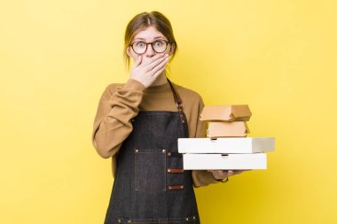 Kızıl saçlı, güzel bir kadın elleri ile ağzını kapatıyor. Fast food yumuşak olsun.