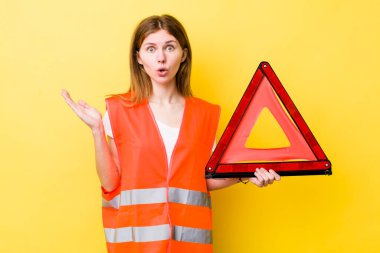 Kızıl saçlı, güzel bir kadın şaşırmış ve şok olmuş görünüyor. Çenesi düşmüş, elinde bir nesne var. Araba üçgeni tehlikesi