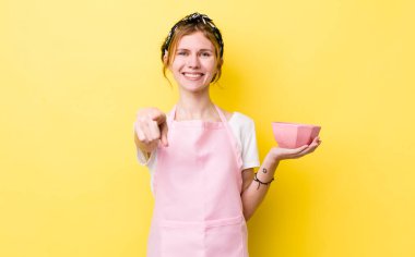 Kızıl saçlı güzel kadın kamerayı işaret ederek seni seçiyor. Ev hanımı elinde boş bir kâse tutuyor.