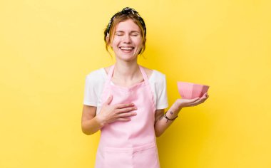 Kızıl saçlı güzel bir kadın komik bir şakaya yüksek sesle gülüyor. Ev hanımı elinde boş bir kâse tutuyor.