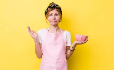 Kızıl saçlı güzel kadın şaşkın, şaşkın ve şüpheci hissediyor. Ev hanımı elinde boş bir kâse tutuyor.