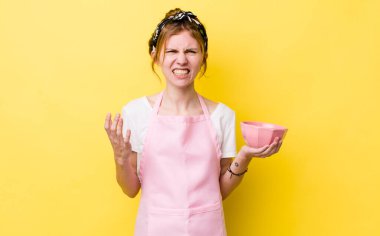 Kızıl saçlı, güzel bir kadın sinirli, sinirli ve sinirli görünüyor. Ev hanımı elinde boş bir kâse tutuyor.