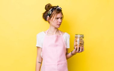 red head pretty woman feeling sad, upset or angry and looking to the side. housewife holding a cookies bottle