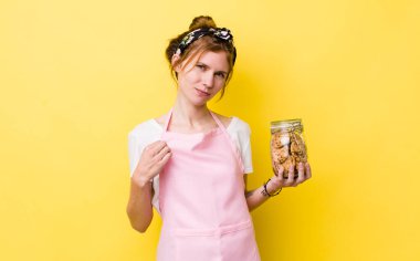 red head pretty woman looking arrogant, successful, positive and proud. housewife holding a cookies bottle