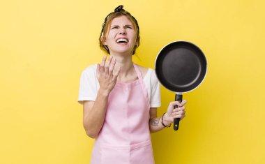 red head pretty woman looking desperate, frustrated and stressed. fry pan and housewife concept