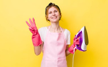 Kızıl saçlı güzel kadın gülümsüyor ve arkadaş canlısı görünüyor, üç numarayı gösteriyor. kahya konsepti