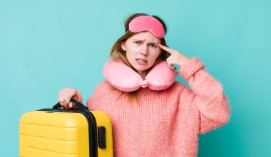 Kızıl saçlı güzel kadın kafası karışık ve şaşkın hissediyor, deli olduğunu gösteriyor. uçuş yolcu kavramı