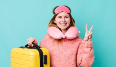 Kızıl saçlı güzel kadın gülümsüyor ve arkadaş canlısı görünüyor, iki numarayı gösteriyor. uçuş yolcu kavramı