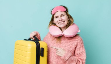 Kızıl saçlı güzel bir kadın neşeyle gülümsüyor, mutlu hissediyor ve bir tarafı işaret ediyor. uçuş yolcu kavramı