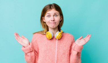Kızıl saçlı güzel kadın şaşkın, şaşkın ve şüpheci hissediyor. kulaklıklar ve müzik konsepti