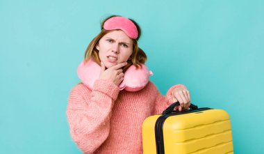 Kızıl saçlı, ağzı ve gözleri açık, eli çenesinde güzel bir kadın. uçuş yolcu kavramı