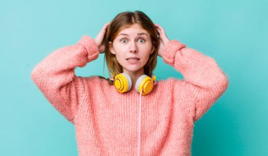 Kızıl saçlı güzel kadın stresli, endişeli ya da korkmuş, elleri başının üstünde. kulaklıklar ve müzik konsepti