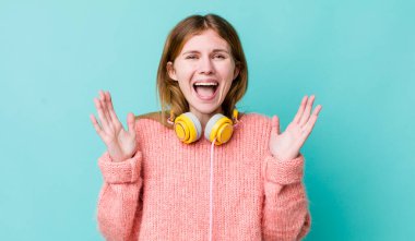 Kızıl saçlı güzel kadın kendini mutlu hissediyor ve inanılmaz bir şeye hayret ediyor. kulaklıklar ve müzik konsepti