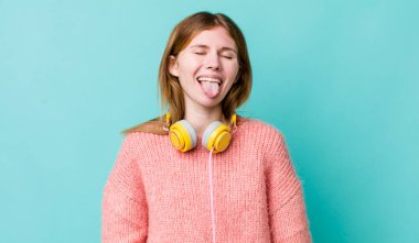 Kızıl saçlı, güzel, neşeli ve asi tavırlı, şaka yapan ve dilini dışarı çıkaran bir kadın. kulaklıklar ve müzik konsepti