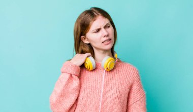 Kızıl saçlı güzel kadın stresli, endişeli, yorgun ve hayal kırıklığına uğramış hissediyor. kulaklıklar ve müzik konsepti