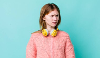 Kızıl saçlı, güzel bir kadın üzgün, üzgün ya da kızgın ve yana bakıyor. kulaklıklar ve müzik konsepti