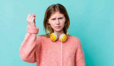 Kızıl saçlı, güzel bir kadın kapiş ya da para hareketi yapıyor, sana ödemeni söylüyor. kulaklıklar ve müzik konsepti