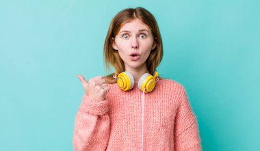 Kızıl saçlı, güzel bir kadın inançsızlıktan şaşkın şaşkın bakıyor. kulaklıklar ve müzik konsepti