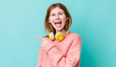 Kızıl saçlı, güzel bir kadın heyecanlı ve şaşırmış görünüyor. kulaklıklar ve müzik konsepti