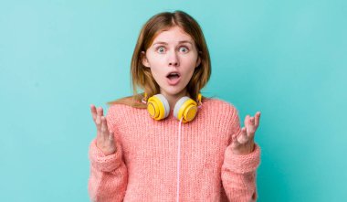 Kızıl saçlı güzel kadın inanılmaz bir sürprizle şaşkına dönmüş ve hayrete düşmüştü. kulaklıklar ve müzik konsepti