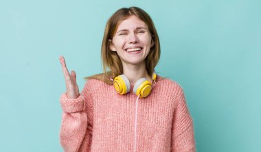 Kızıl saçlı güzel kadın kendini mutlu hissediyor, bir çözüm ya da fikir bulduğuna şaşırıyor. kulaklıklar ve müzik konsepti