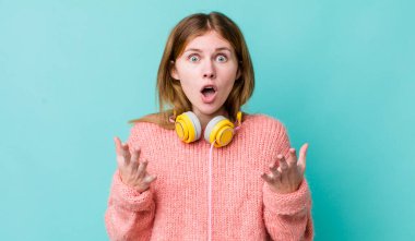 Kızıl saçlı güzel kadın çok şaşırmış ve şok olmuş hissediyor. kulaklıklar ve müzik konsepti