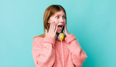 Kızıl saçlı güzel kadın mutlu, heyecanlı ve şaşırmış hissediyor. kulaklıklar ve müzik konsepti