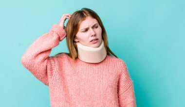 Kızıl saçlı güzel kadın şaşkın ve kafası karışık, kaşınan bir kafa hissediyor. kaza tasması konsepti