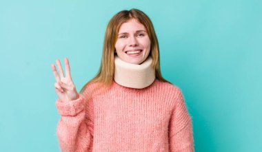 Kızıl saçlı güzel kadın gülümsüyor ve arkadaş canlısı görünüyor, üç numarayı gösteriyor. kaza tasması konsepti