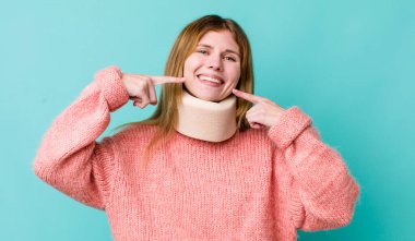 Kızıl saçlı, güzel bir kadın kendi gülüşünü işaret ediyor. kaza tasması konsepti