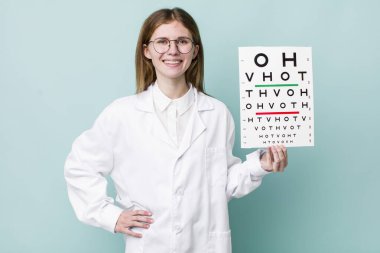 Kızıl saçlı güzel kadın mutlu bir şekilde gülümsüyor, eli kalçasında ve kendinden emin. optik görüş testi konsepti