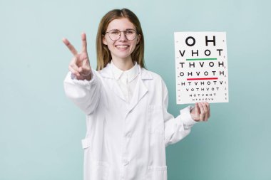 Kızıl saçlı güzel kadın gülümsüyor ve mutlu görünüyor, zafer ya da barış işareti yapıyor. optik görüş testi konsepti