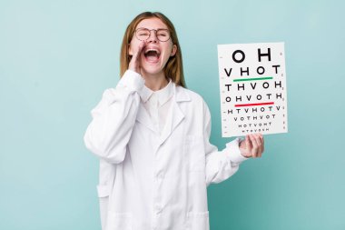 Kızıl saçlı, güzel bir kadın kendini mutlu hissediyordu. Elleri ağzının kenarında bağırıyordu. optik görüş testi konsepti