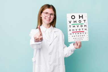 Kızıl saçlı güzel kadın gururla gülümsüyor ve kendinden emin bir numara oluyor. optik görüş testi konsepti