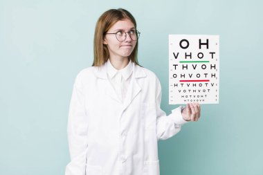 Kızıl saçlı güzel kadın omuz silkiyor, kafası karışık ve kararsız. optik görüş testi konsepti