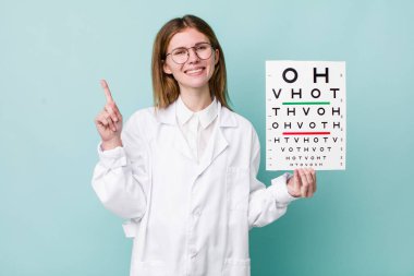 Kızıl saçlı güzel kadın gülümsüyor ve arkadaş canlısı görünüyor, bir numarayı gösteriyor. optik görüş testi konsepti