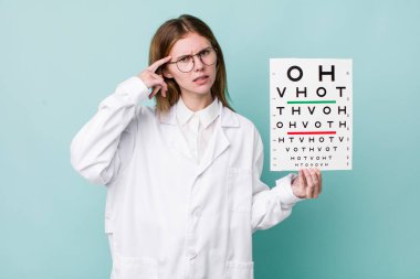 Kızıl saçlı güzel kadın kafası karışık ve şaşkın hissediyor, deli olduğunu gösteriyor. optik görüş testi konsepti