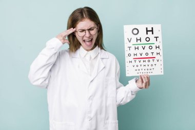 Kızıl saçlı güzel bir kadın mutsuz ve stresli görünüyor, intihar jesti silah işareti yapıyor. optik görüş testi konsepti