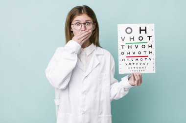 Kızıl saçlı, güzel bir kadın elleri ile ağzını kapatıyor. optik görüş testi konsepti