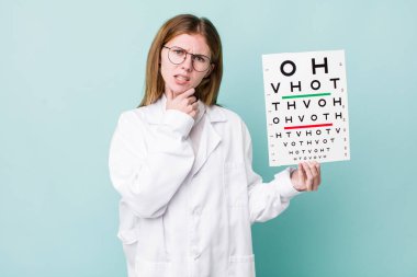 Kızıl saçlı, ağzı ve gözleri açık, eli çenesinde güzel bir kadın. optik görüş testi konsepti