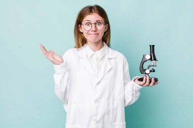 Kızıl saçlı güzel kadın şaşkın, şaşkın ve şüpheci hissediyor. Mikroskop konseptine sahip bilim adamı