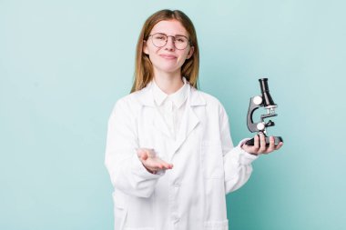 Kızıl saçlı, güzel bir kadın arkadaşça gülümsüyor ve bir konsept sunuyor. Mikroskop konseptine sahip bilim adamı