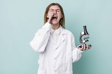 Kızıl saçlı, güzel bir kadın kendini mutlu hissediyordu. Elleri ağzının kenarında bağırıyordu. Mikroskop konseptine sahip bilim adamı