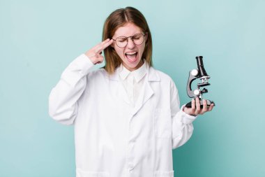 Kızıl saçlı güzel bir kadın mutsuz ve stresli görünüyor, intihar jesti silah işareti yapıyor. Mikroskop konseptine sahip bilim adamı