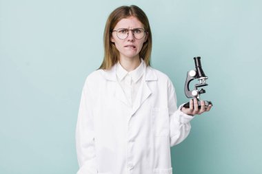 Kızıl saçlı güzel kadın kafası karışık ve şaşkın görünüyor. Mikroskop konseptine sahip bilim adamı